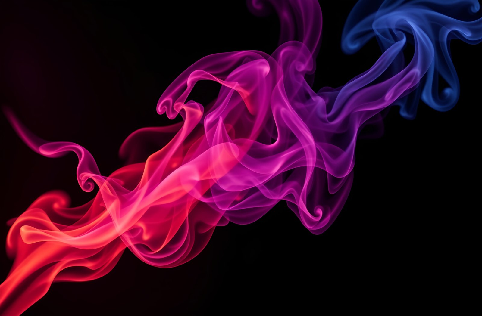 Elegant swirls of colorful smoke creating fluid patterns against dark black background
