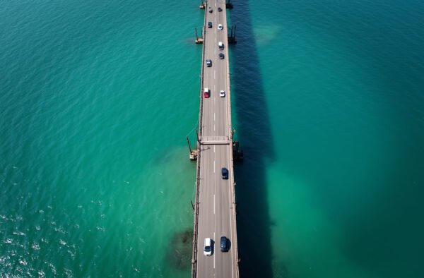 dramatic aerial view of a long bridge stretching over turquoise ocean waters with cars crossing