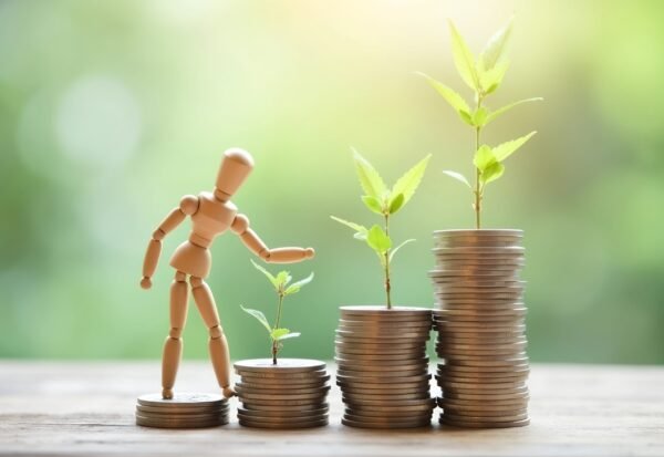 Wooden figure standing on a stack of coins ,savings, financial growth, or ambition