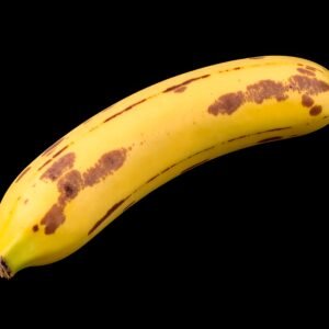 Overripe banana with brown spots isolated on black background—free image for food, baking or texture visuals.