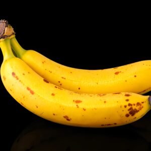 Two overripe bananas with brown spots isolated on black background