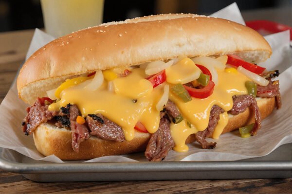 Philly cheesesteak sandwich on a rustic metal tray, thin-sliced beef, melted provolone