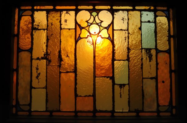 Antique stained textured glass with aged color tint, illuminated softly