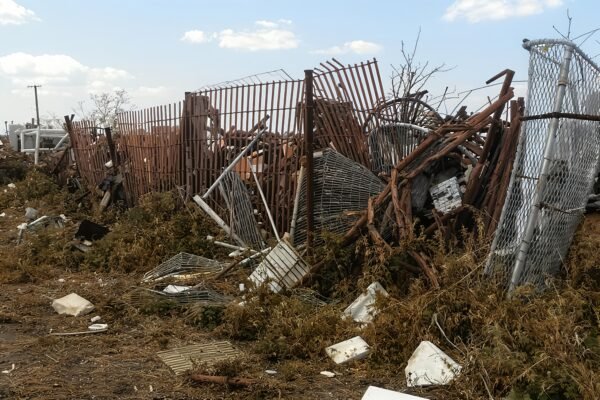 Photorealistic junkyard scene with broken rusted fences, crushed metal objects, and weeds growing through the pile