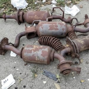 Clusters of rusted car parts lying on a concrete ground—industrial texture photo