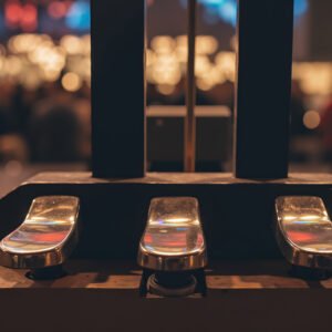 Piano pedal in sharp focus with blurred concert stage background capturing live performance atmosphere