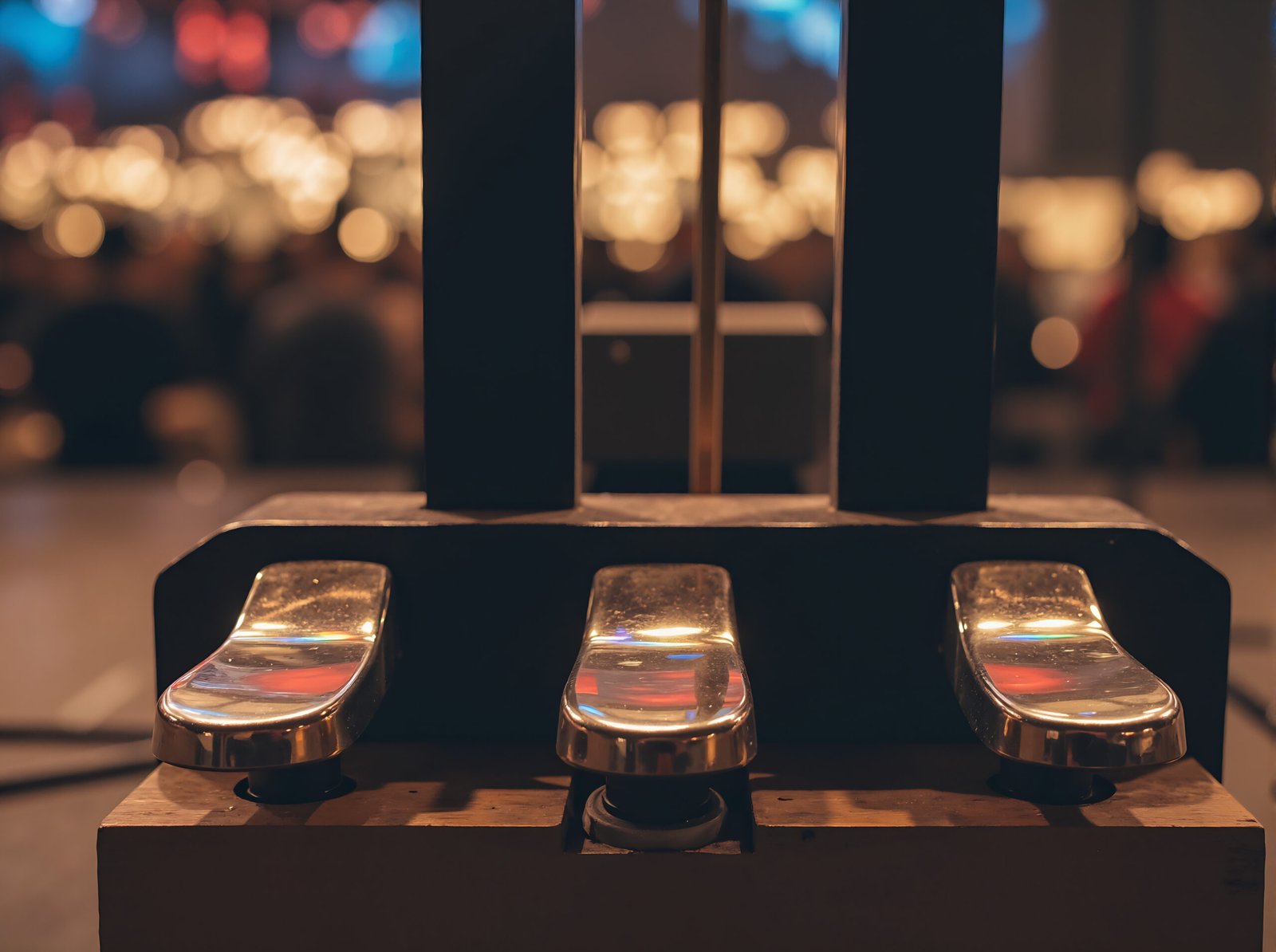 Piano pedal in sharp focus with blurred concert stage background capturing live performance atmosphere