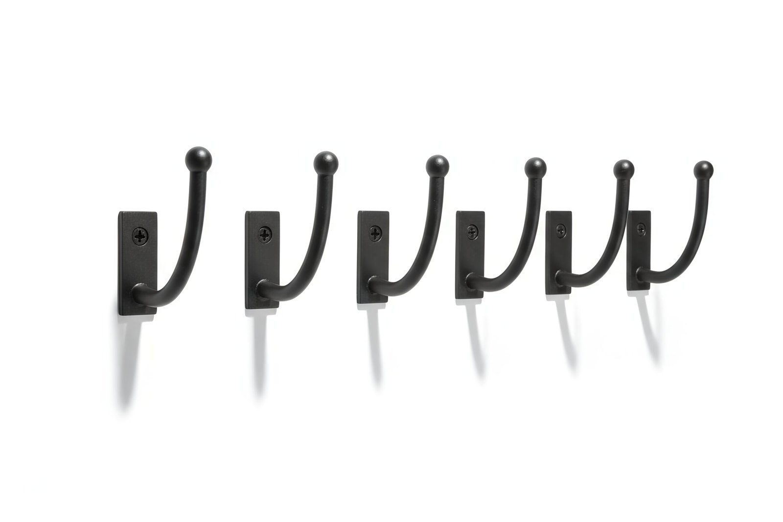 Black metal wall hooks row isolated on white background sharp shadows product style photography