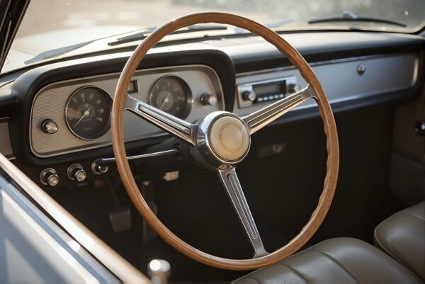 Close up of a simple retro car steering wheel inside classic vehicle blurred dashboard background natural daylight