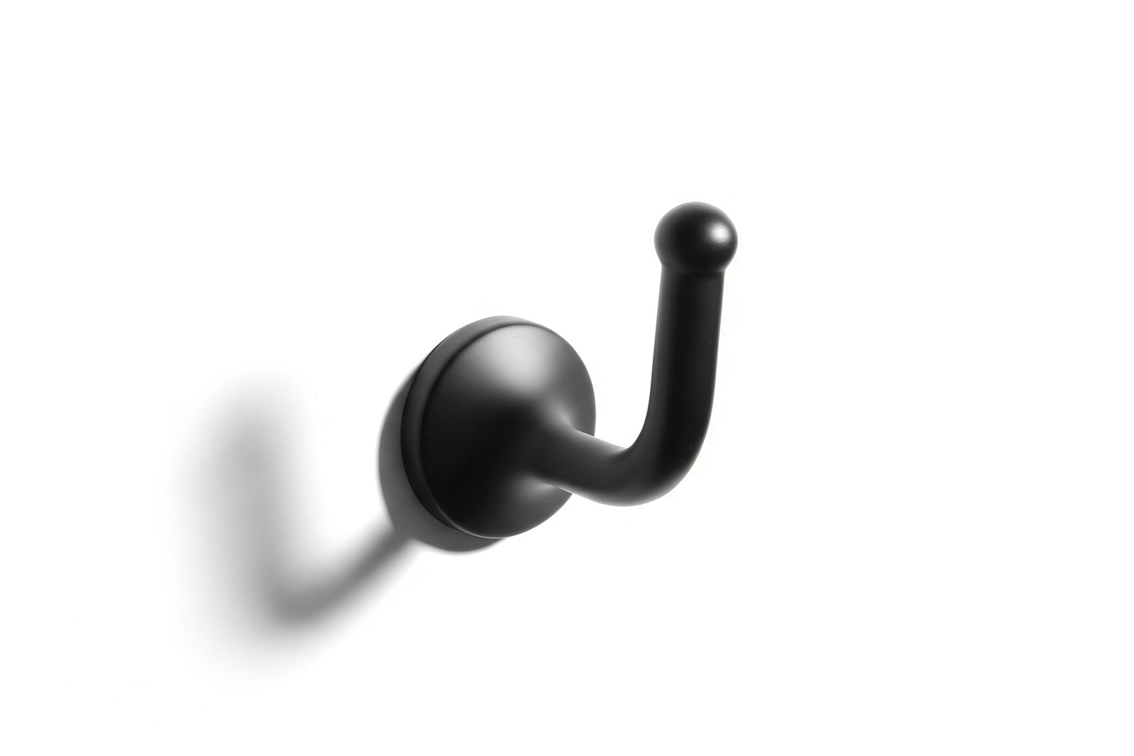 One Black metal wall hook isolated on white background sharp shadows product style photography