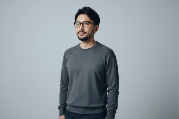 Studio portrait of a Japanese man with glasses minimalist gray backdrop calm expression