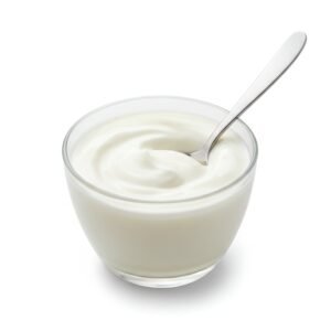 cup of yogurt with smooth creamy texture and spoon inserted studio lighting minimal shadows white backdrop no branding or text