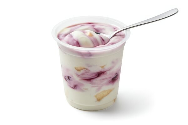 fruit yogurt in transparent cup with spoon creamy texture visible isolated on white clean product style photography