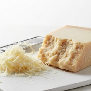 parmesan cheese block with freshly grated cheese beside it macro detail clean white backdrop high resolution food photography