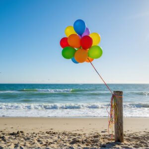 Download this colorful birthday balloons photo on sunny beach, perfect for party invitations, festive marketing visuals, and summer greeting designs.